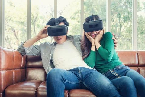 Young Couple Having Fun While Watching Video Via Virtual Reality Together Stock Photos