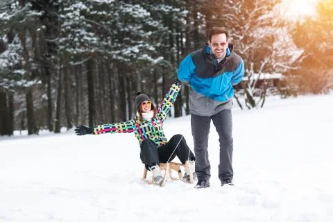 Young couple having fun in winter nature with sleigh Stock-Fotos