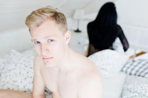 Young couple having problems in bed. Blue eyed handsome man and woman bother Stock Photos