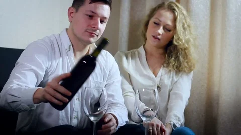 Young Couple Having Red Wine at Home. Man Pouring Alcohol From Bottle to the Stock Footage 71534654
