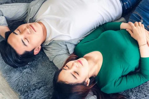 Young Couple Having Relaxing While Lying on Carpet at Their Home, Attractive Foto stock