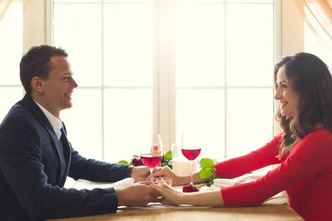 Young couple having romantic dinner in the restaurant holding hands smiling Stock Photos