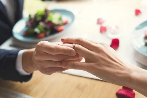 Young couple having romantic dinner in the restaurant wearing a proposal ring Stock Photos