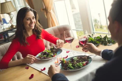Young couple having romantic dinner in the restaurant eating salad smiling Stock Photos