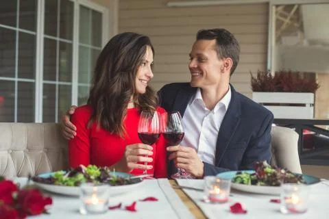 Young couple having romantic dinner in the restaurant sitting together looking Stock Photos
