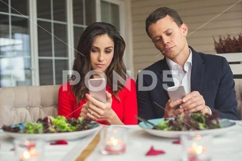 Young couple having romantic dinner in the restaurant phone addiction Stock Photos