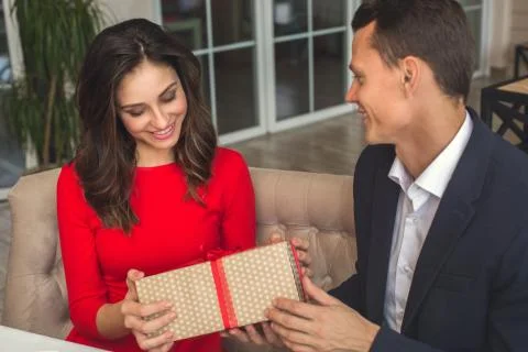 Young couple having romantic dinner in the restaurant holding a present box Stock Photos