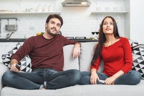 Young couple having romantic evening at home watching program Stock Photos