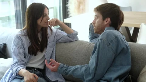 Young couple having a serious conversation while sitting on the sofa at home, d Stock Footage 334105978