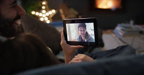 Young couple having video chat at home in front of fireplace holding smartphone Stock Footage 73369976