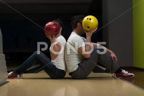 Young couple hiding their faces behind bowling ball Stock Photos
