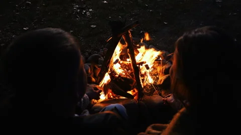A young couple on a hike sit by a campfire, roasting marshmallows. Stock Footage 318698697