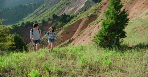 A young couple Hiking in the mountains for a sunrise walk holding hands, slow Stock Footage