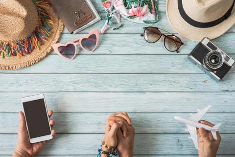 Young couple holding empty screen smart phone with travel summer accessories  库存照片