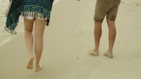 Young couple holding hands and walking along the beach near the water in Austral Stock Footage 199463500