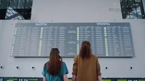 Young couple holding hands checking airport departures board 库存影片 334567160