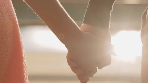 Young couple holding hands, looking at each other in a bright sunshine by lake 库存影片 71785869