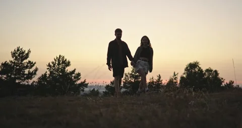 A young couple holding hands while walking against the background of the sky. Stock Footage 264488577