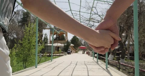 Young couple holding hands while walking together in park. Romantic couple in Stock Footage 270976928