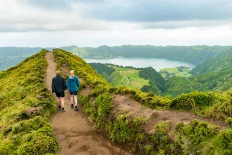 A young couple holding hands while walking towards the viewpoint at Sete Cidades Foto stock