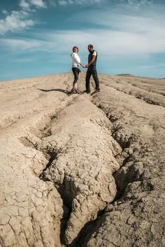 Young couple holding hands while staying on cracked dry soil Stock Photos