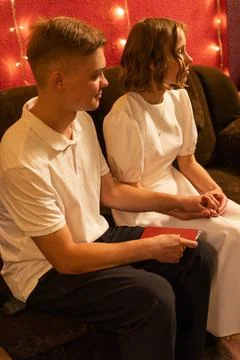 Young couple holding hands while sitting close together on a couch with fai.. Фото