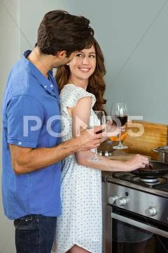 Young Couple Holding Wine Glass In Kitchen