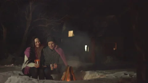 Young couple with hot drinks by fire. Stockbeeldmateriaal 106458676