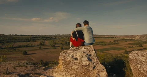 Young couple hugging while sitting on a cliff with a beautiful view. Stock Footage 108784038