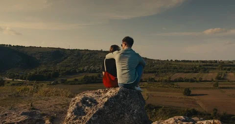 Young couple hugging while sitting on a cliff with a beautiful view. Stock Footage 108784214