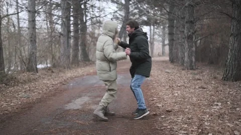 Young couple humorously dancing together in park outdoors, warmly dressed, Vídeos de archivo 336737810