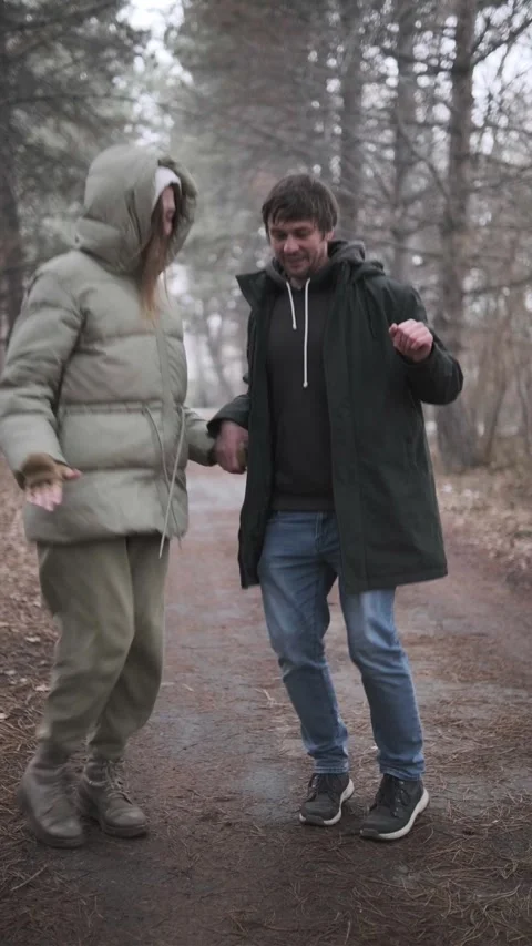 Young couple humorously dancing together in park outdoors, warmly dressed, Vídeos de archivo 336737879