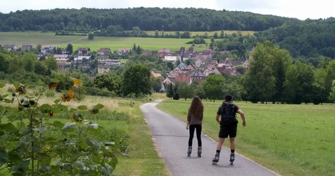 Young couple inline skating at  bicycle path along the Main river, Germany Stock Footage 118922980