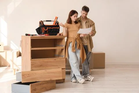 Young couple with instructions assembling chest of drawers at home Stock Photos