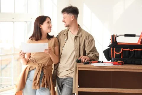 Young couple with instructions assembling chest of drawers at home Stock Photos