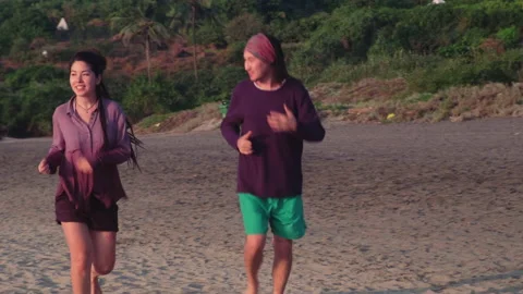 Young couple jogging on a beach at sunset Stock Footage 158092809
