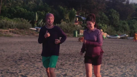 Young couple jogging on a beach at sunset Stock Footage 162811558