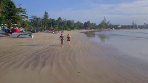 Young couple jogging on the empty beach morning time drone footage Stock Footage 84883714
