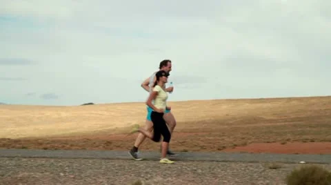 Young couple jogging, exercising and drinking water on desert road, slow motion Vídeos de archivo 10842362