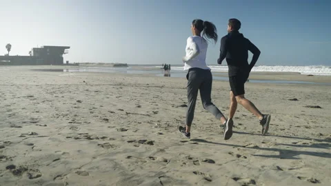 Young Couple Jogs on the Beach in Slow Motion Stock Footage 233386569