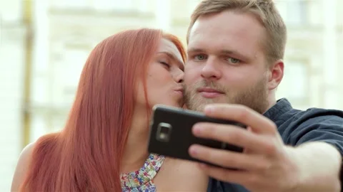 Young couple joyfully capturing a selfie in a vibrant urban park Stock Footage 311815606