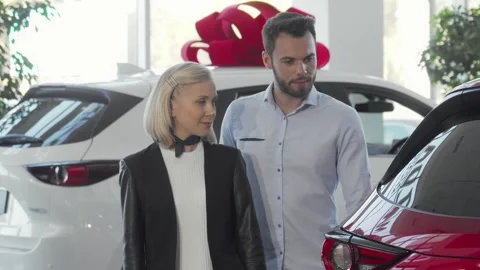 Young couple joyfully selecting their dream car at a vibrant dealership Stock Footage 311989023