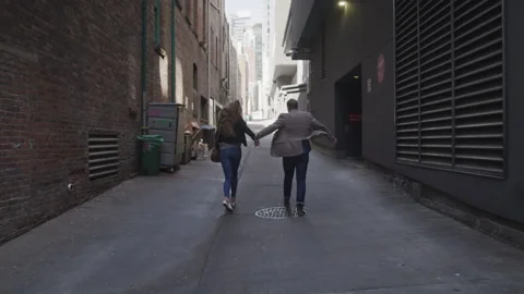 Young Couple Joyfully Walk Through an Alleyway Vídeo Stock 208718637
