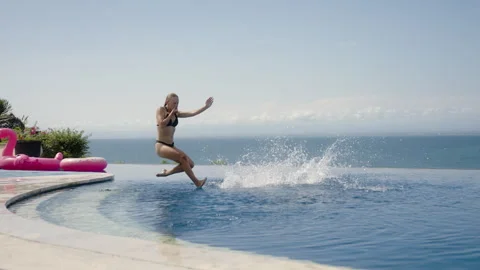 Young couple jump in ocean view infinity pool on luxury private villa Stock Footage 259158528