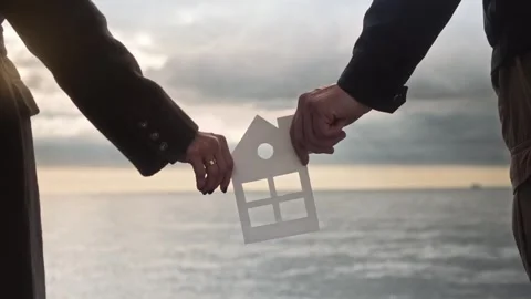 Young couple keep a beautiful paper house dreaming of their own home by the sea Stock Footage 307594983