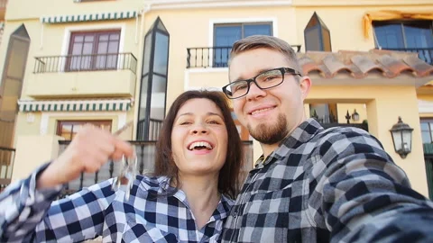 Young Couple with keys standing outside new home and taking a selfie Stock Footage 88940485