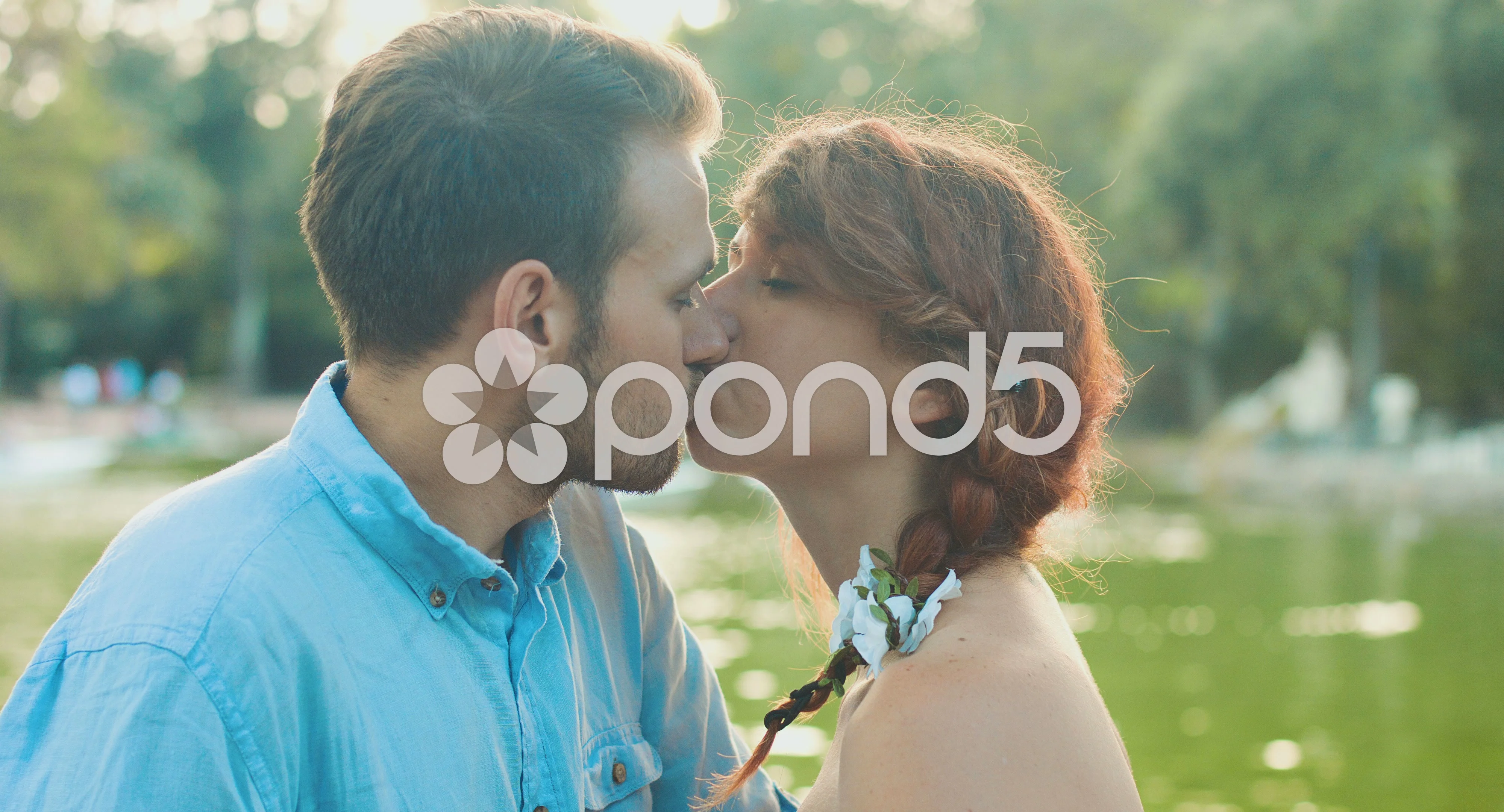 young couple kissing in front of small lake in a public garden: romantic  date