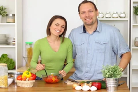 Young couple in the kitchen preparing vegetable salad and smiling NTSC Stock Footage 8988070
