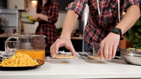 Young couple in the kitchen, puts on the table baked chicken for dinner Stock Footage 104327993