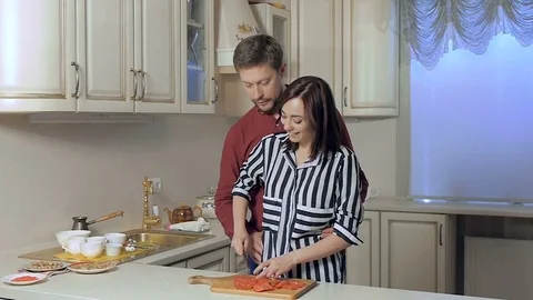 A young couple in the kitchen slicing tomatoes on a cutting board. Preparation Stock Footage 78018631